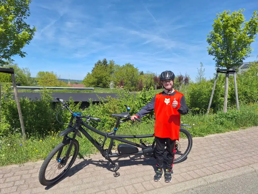 Linus Manzi steht vor seinem tandem und macht die Daumen hoch Geste